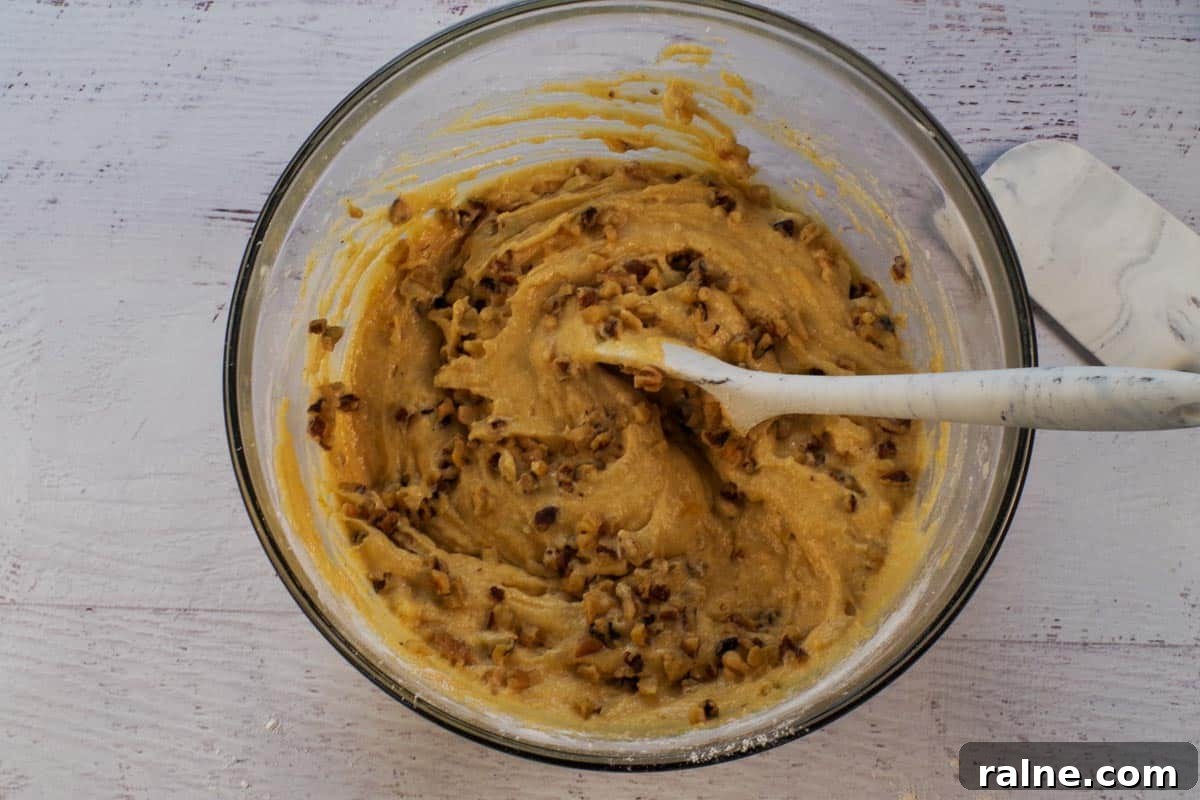 Dairy-Free Pumpkin Walnut Bread Recipe 11 Nuts mixed into pumpkin mixture in large glass bowl.