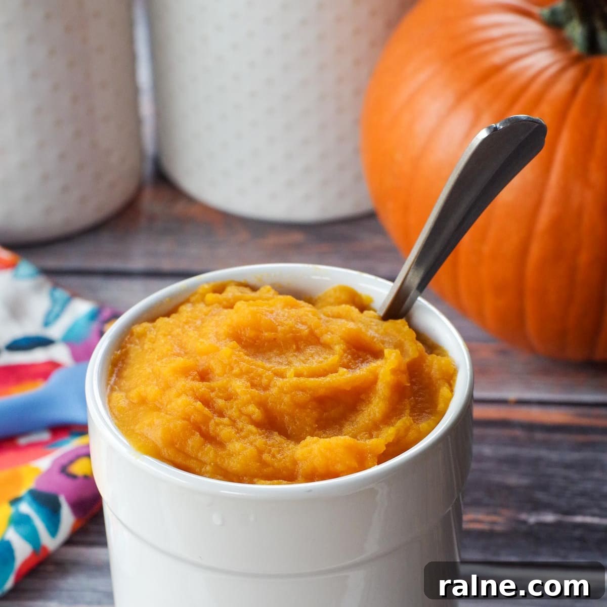 Dairy-Free Pumpkin Walnut Bread Recipe 4 white canister with pumpkin puree in it, as well as spoon and whole pumpkin in background