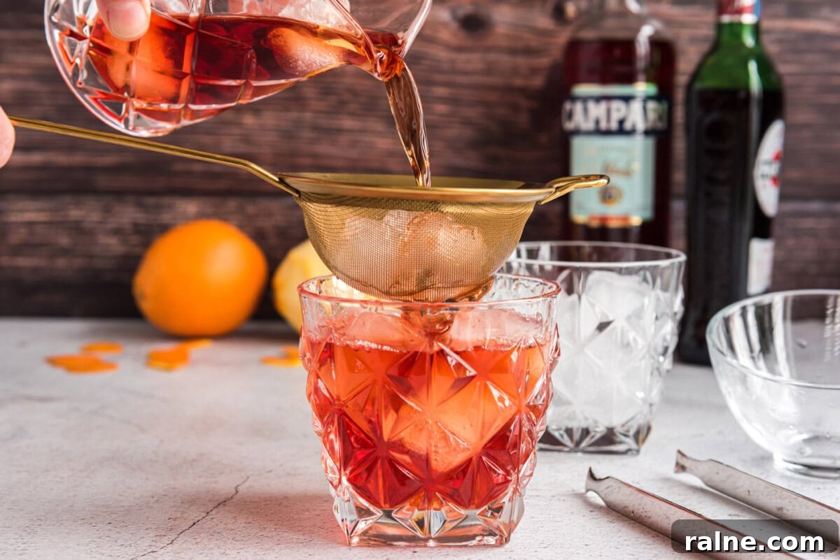 straining ingredients for Negroni into a rock glass
