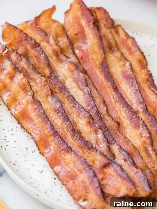 Hearty Breakfast Casserole Recipe for Busy Mornings 9 Strips of bacon in the oven on a round speckled white plate