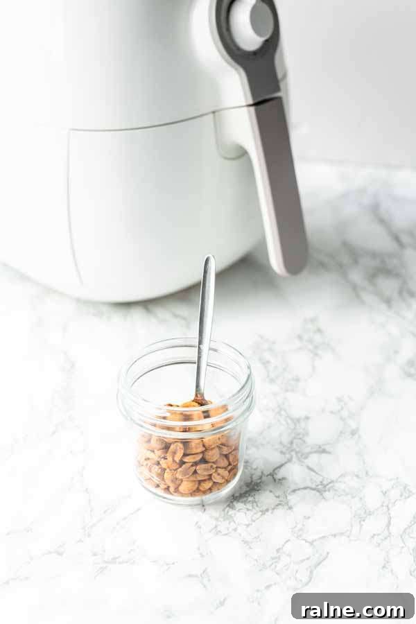 Crispy Homemade Air-Fried Peanuts Recipe 7 Roasted Air Fryer peanuts in a glass jar with a spoon. Easy to make yourself in no time.