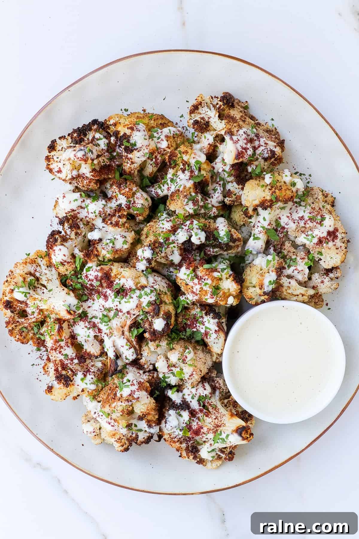 Sumac-Roasted Cauliflower with Creamy Tahini Sauce 8 Lebanese style cauliflower on a plate with tahini sauce.