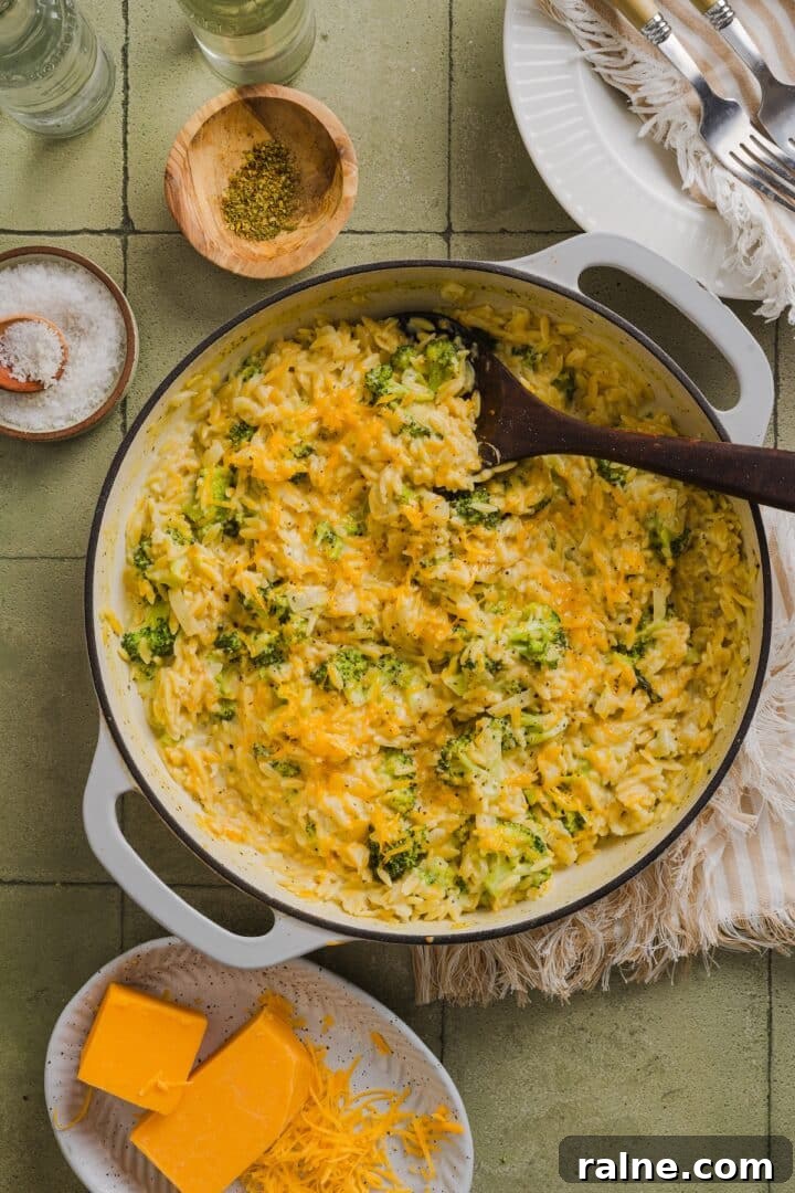 Creamy Broccoli Cheddar Orzo Bake with Parmesan Crust 2 One-pot broccoli cheddar orzo in a braiser pan on a green tile counter.