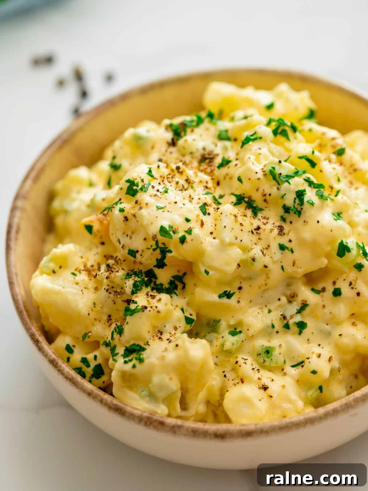 Old-Fashioned Potato Salad dished in large bowl topped with crushed pepper and parsley.