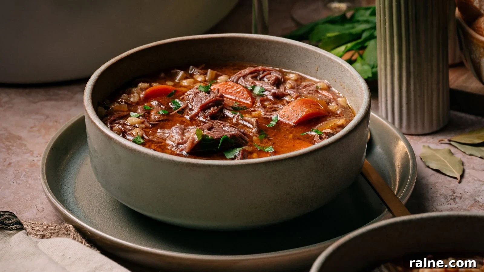 17 Comforting Soup Recipes for Quiet Evenings 6 Hearty slow-cooked beef and barley soup filled with tender short rib pieces in a deep bowl.