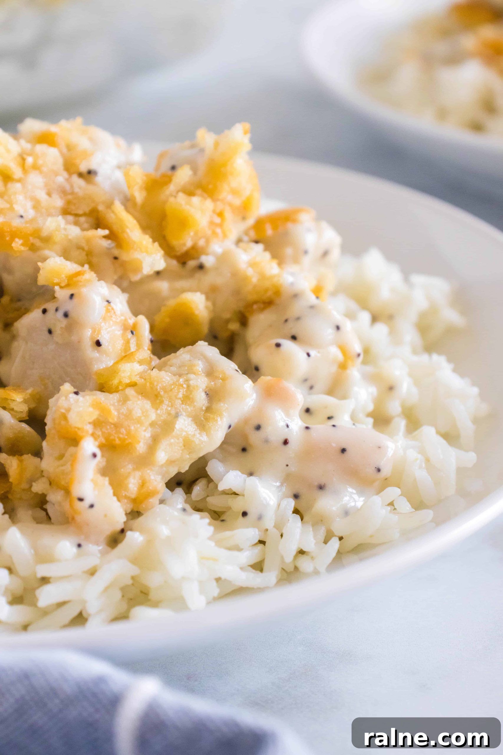 Creamy Poppy Seed Chicken Casserole with Ritz Topping 9 Cooked white rice on a white dinner plate and topped with creamy, saucy poppy seed chicken casserole.