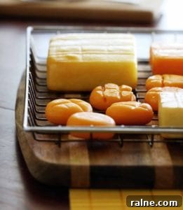 Smoked Cheddar Cheese: Flavorful Uses, Pairings, and Buying Guide 3 A wire basket on a wood cutting board containing several types of cheese, including smoked cheddar cheese.