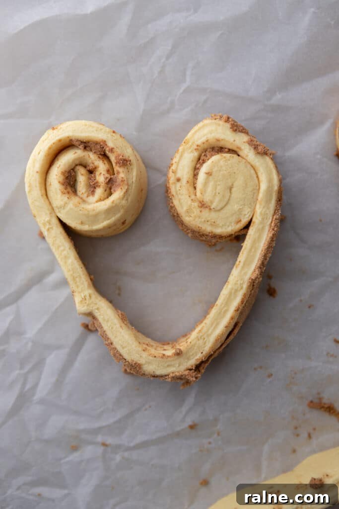 Unbaked cinnamon roll dough shaped into a heart on parchment paper