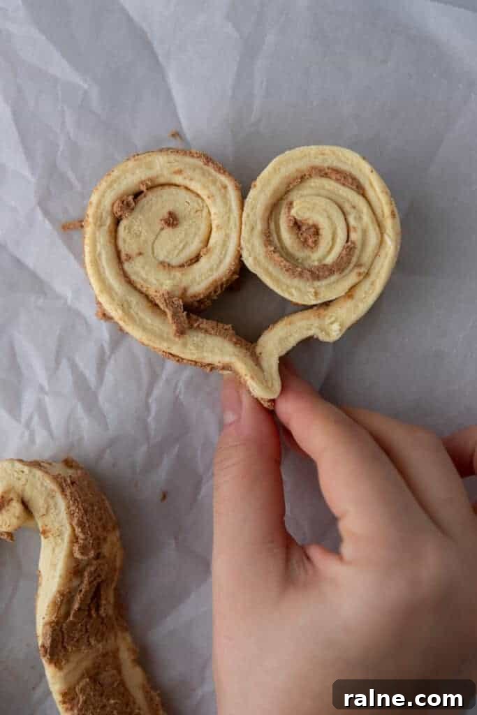 Hands shaping cinnamon roll dough into a heart shape