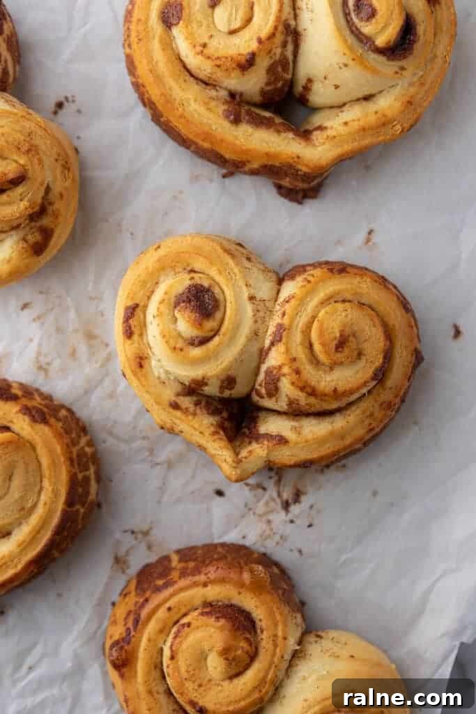 Baked heart-shaped cinnamon rolls without frosting on parchment paper
