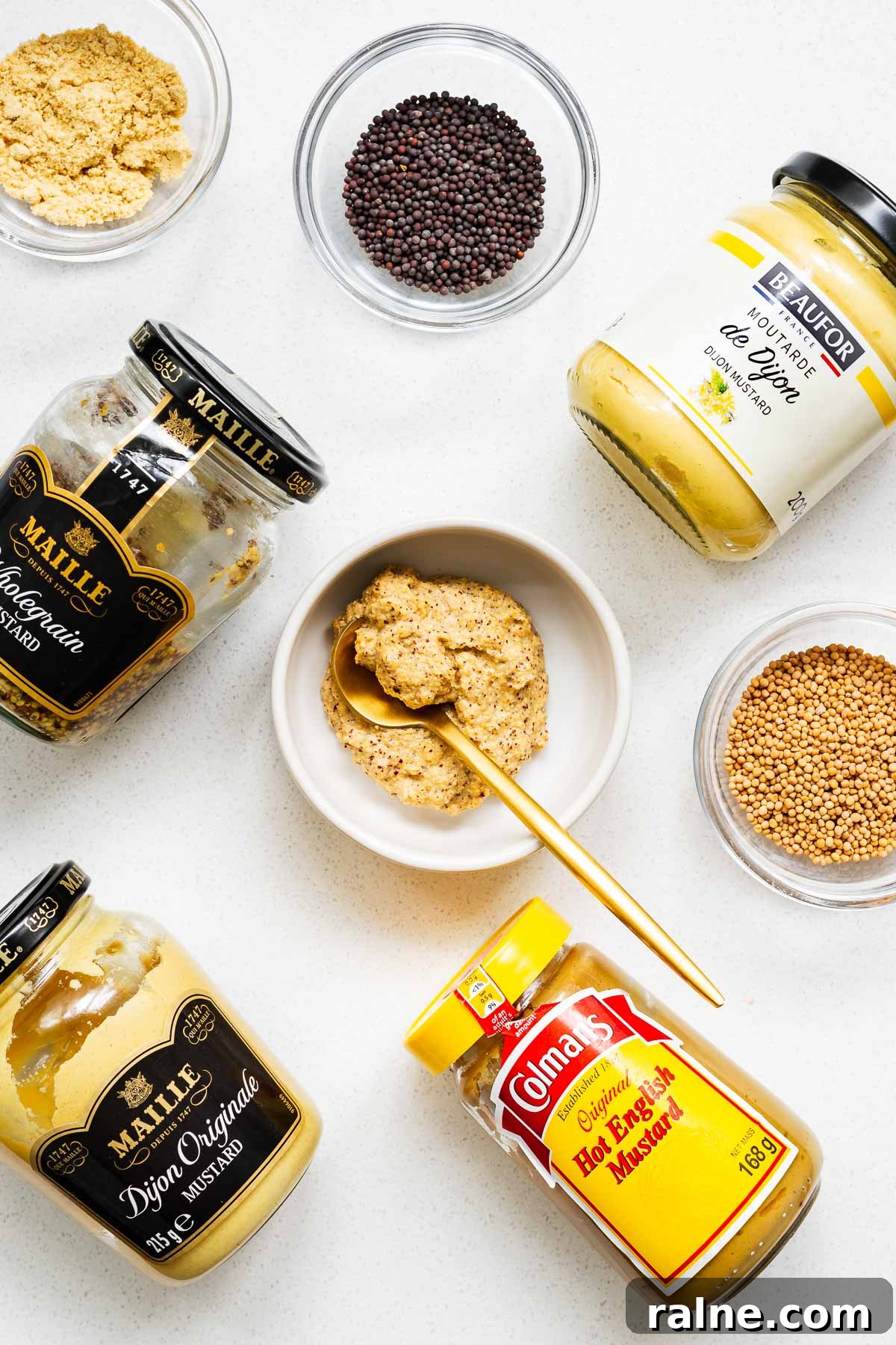 Dijon Mustard Substitutes and Simple Homemade Recipe 2 Jars of Dijon mustard and suitable substitutes arranged on a kitchen towel with small bowls of mustard seeds and mustard powder.