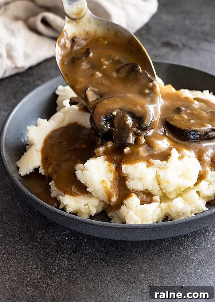 Creamy Mushroom Gravy Recipe for Roasts and Mashed Potatoes 5 Gravy being spooned over mashed potatoes.