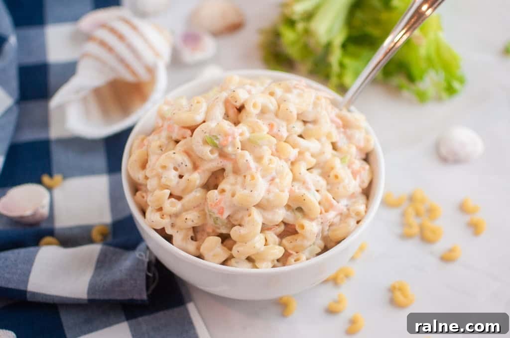 23 Make-Ahead Salads That Stay Fresh in the Fridge and Lunch Bag 12 A white bowl filled Hawaiian with macaroni salad with a spoon inside.