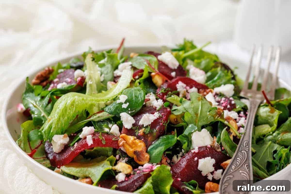 23 Make-Ahead Salads That Stay Fresh in the Fridge and Lunch Bag 14 A Beet Salad with Goat Cheese and Walnuts in a white bowl, accompanied by a fork.