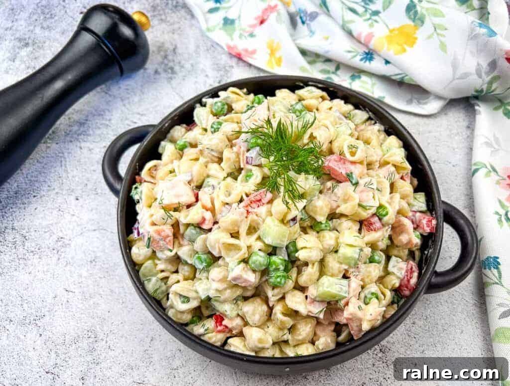 23 Make-Ahead Salads That Stay Fresh in the Fridge and Lunch Bag 22 A bowl of salmon pasta salad with a creamy dressing, garnished with a sprig of dill.