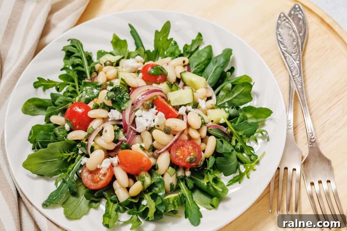 23 Make-Ahead Salads That Stay Fresh in the Fridge and Lunch Bag 24 A plate of white bean salad on a wooden surface next to two vintage forks.