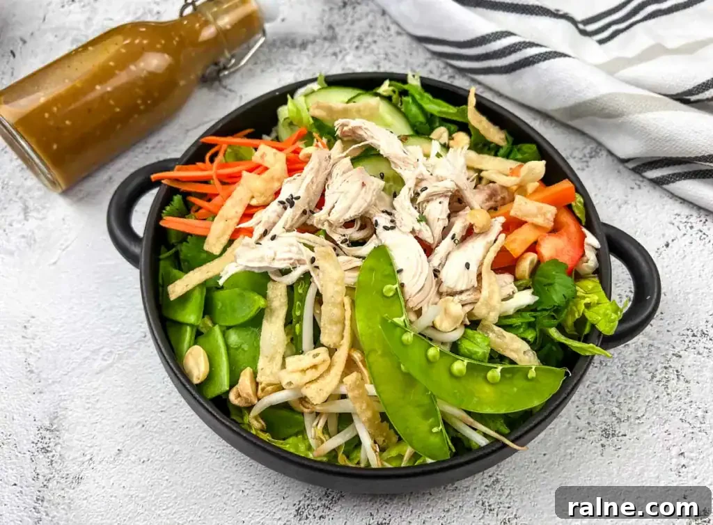 23 Make-Ahead Salads That Stay Fresh in the Fridge and Lunch Bag 6 A bowl of Chinese chicken salad with shredded chicken, snap peas, carrots, and peppers, accompanied by a bottle of dressing on the side.