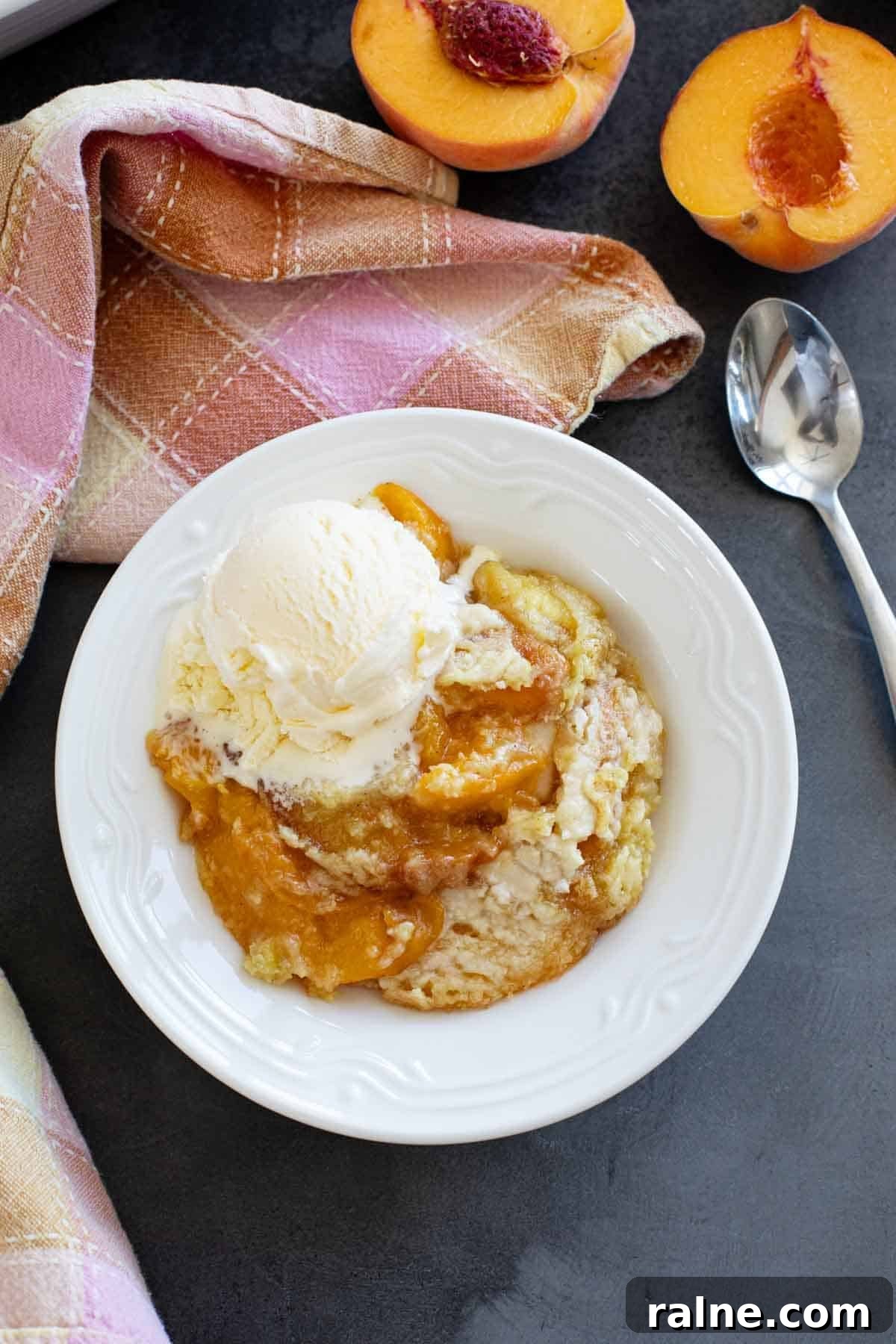 Bowl of peach dump cake with a scoop of vanilla ice cream on top.