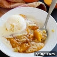 Bowl of peach dump cake topped with ice cream.