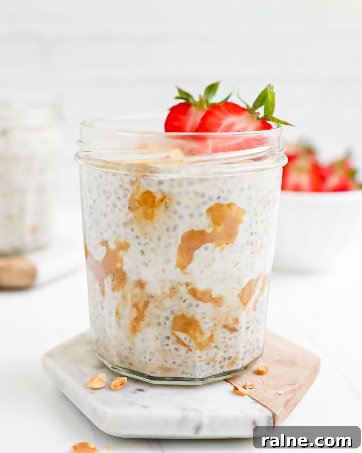 A mason jar filled with peanut chia seed pudding and strawberries.