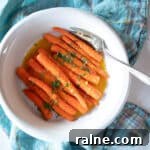 Honey-Ginger Glazed Carrots Recipe for Holiday Sides 4 Serving dish of braised citrus ginger carrots with a serving fork.