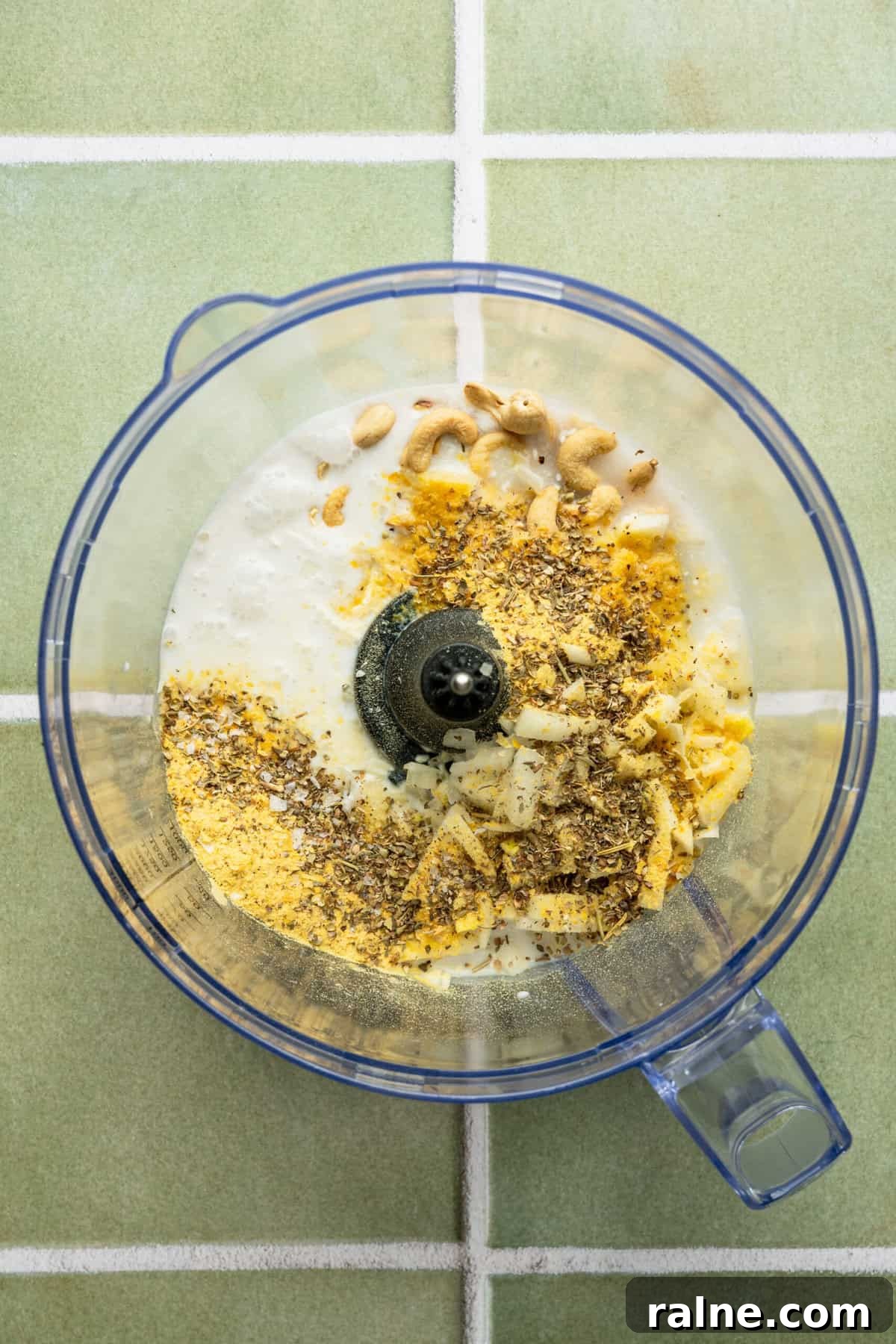 A blender with cashews, milk and nutritional yeast in it.