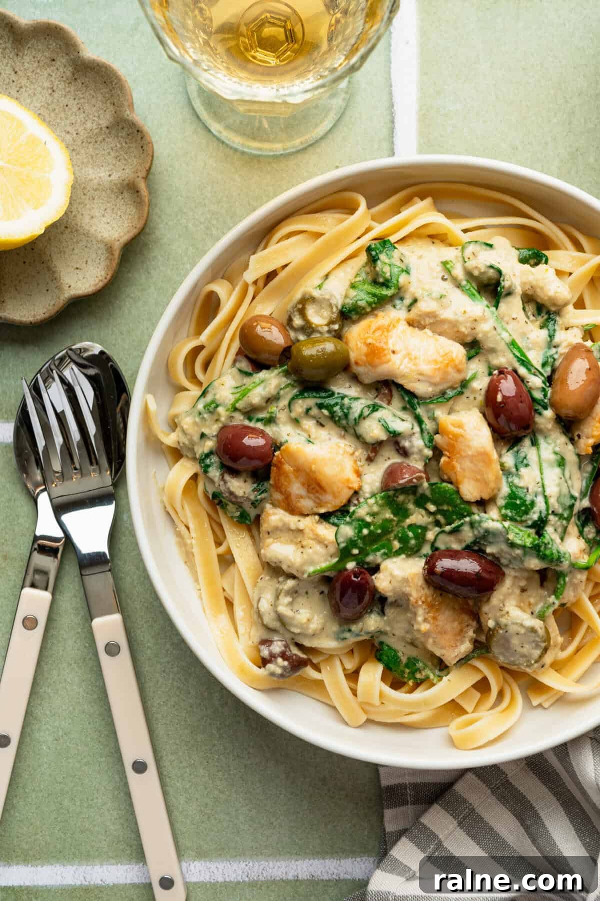A bowl of cooked pasta noodles topped with a chicken Alfredo sauce.