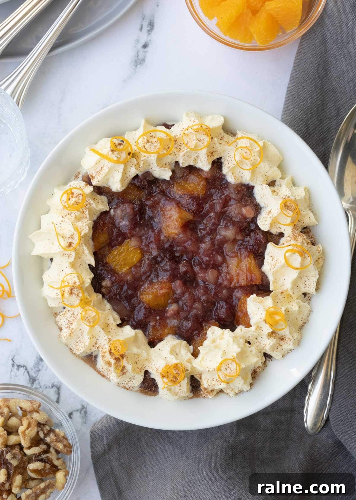 A cranberry, orange, pineapple and walnut salad in a white bowl with a silver spoon.