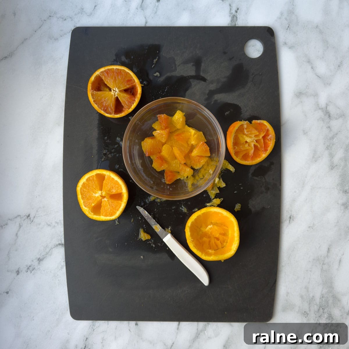Cutting orange segments from oranges with a paring knife.