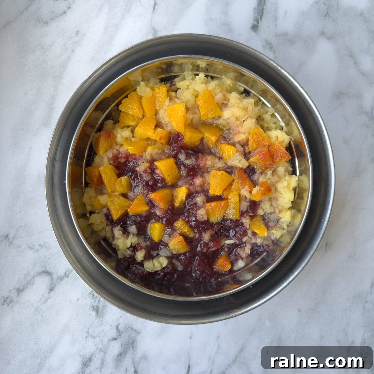 Fruit for a cranberry salad draining in a colander.