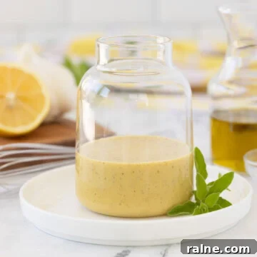 Golden creamy Greek salad dressing in a glass jar on a counter.