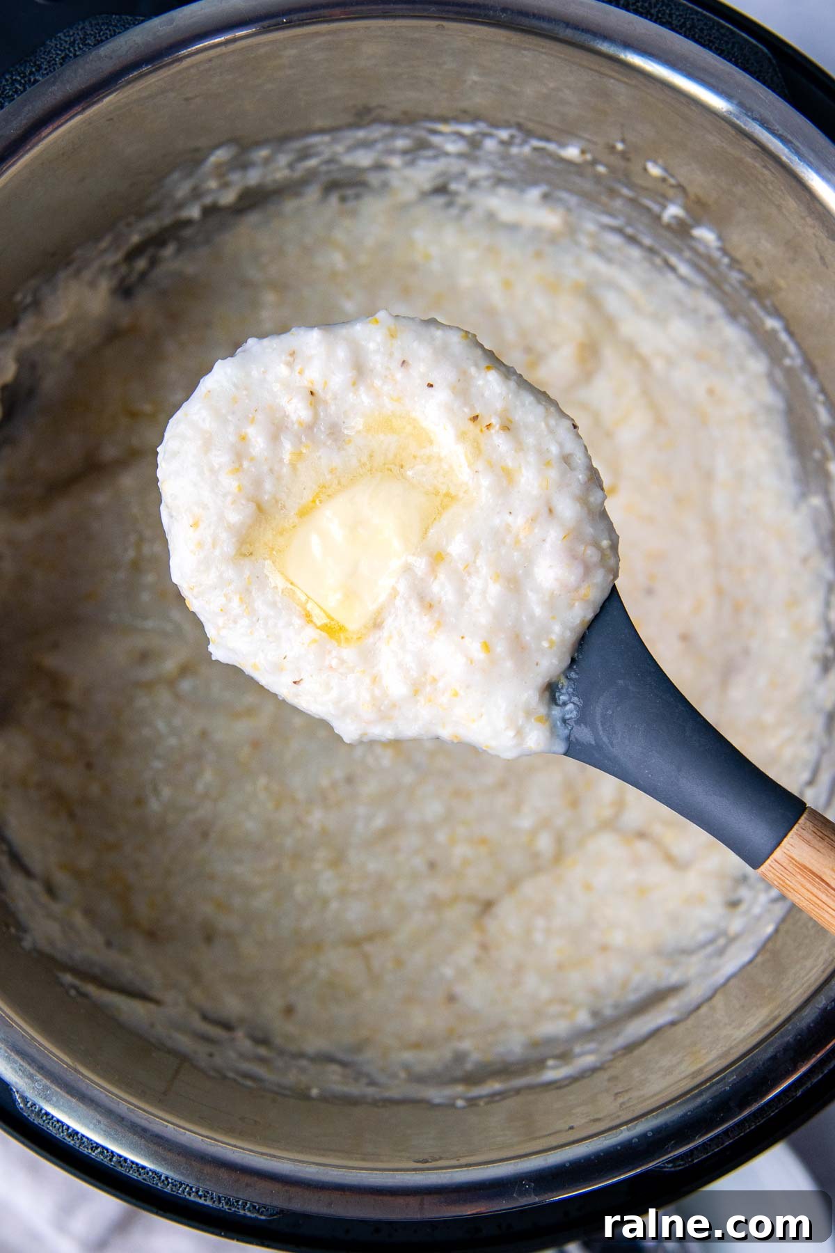 a scoop of grits with melted butter on top being held up from an instant pot.