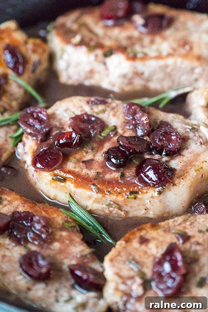 Skillet Pork Chops topped with cranberries and port wine in a skillet.
