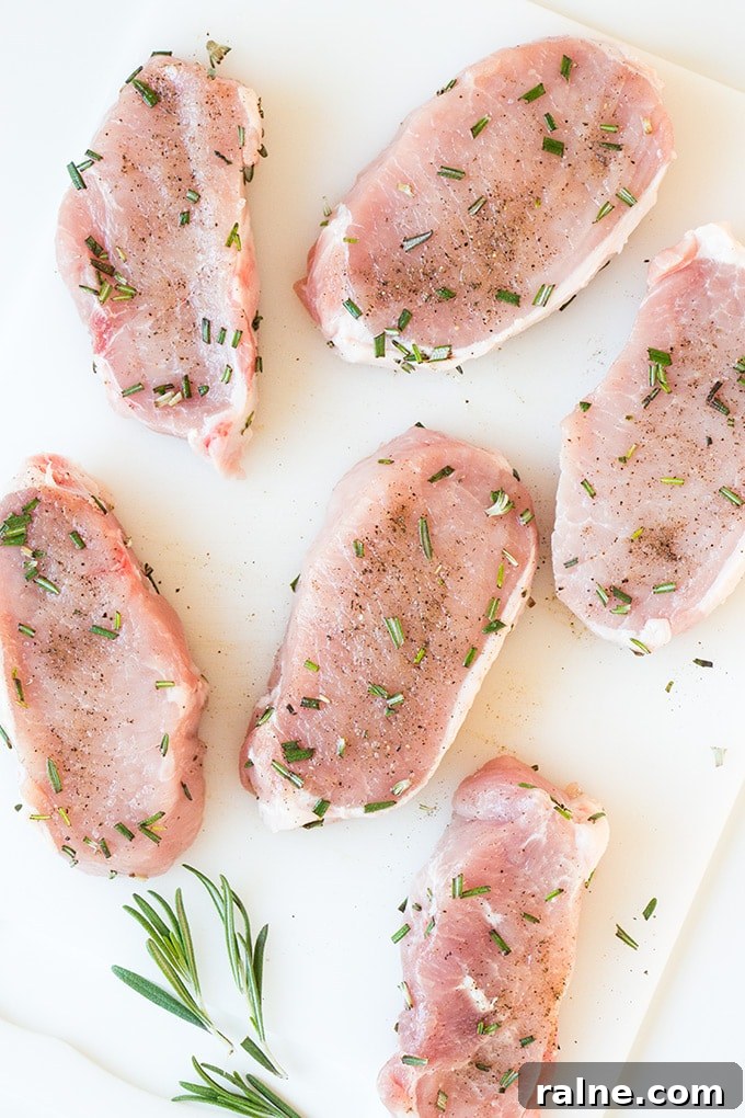 Raw pork chops seasoned with chopped rosemary