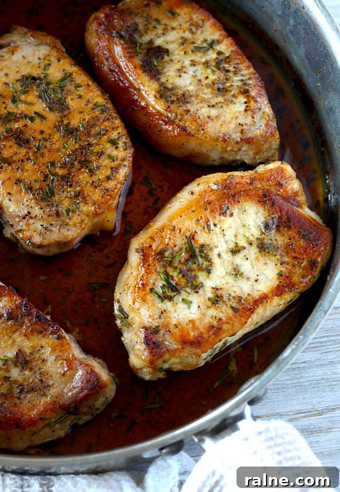 Golden seared pork chops inside a skillet.