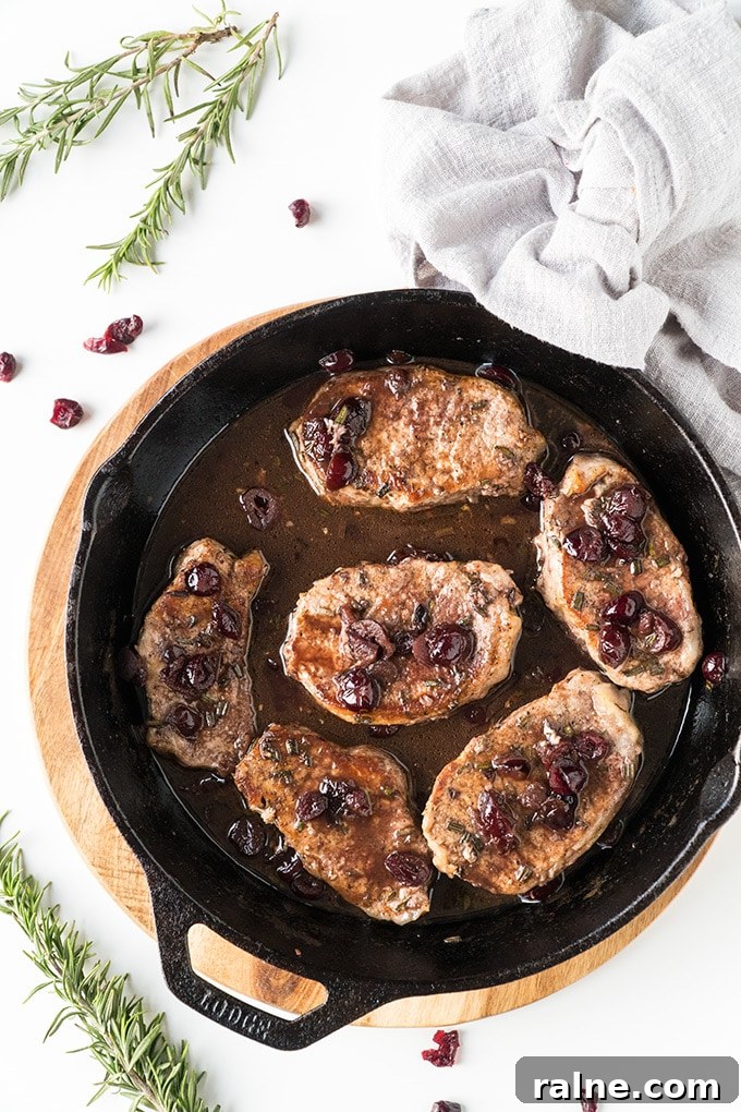 Top view of skillet pork chops topped with port wine and cranberries.
